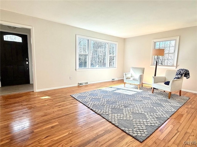 sitting room with wood finished floors, a wealth of natural light, baseboards, and visible vents