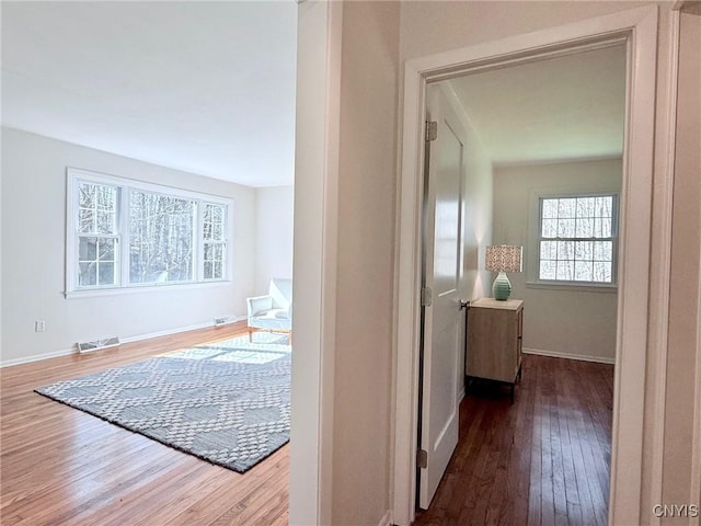 hallway featuring wood finished floors, visible vents, and baseboards