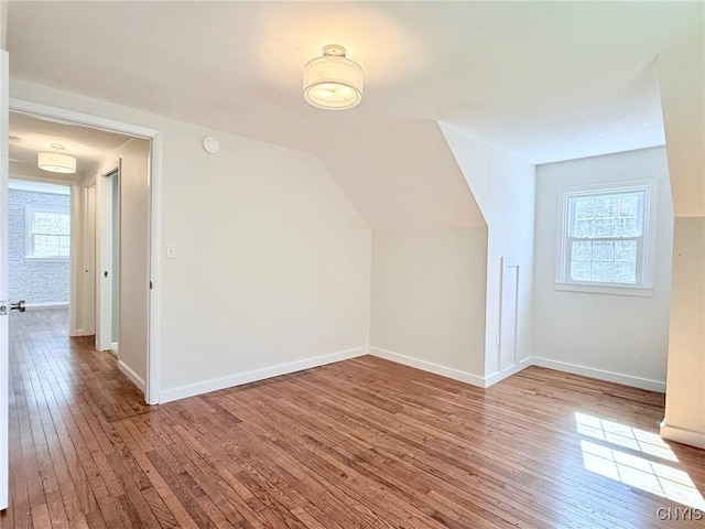 bonus room with hardwood / wood-style floors, lofted ceiling, and baseboards