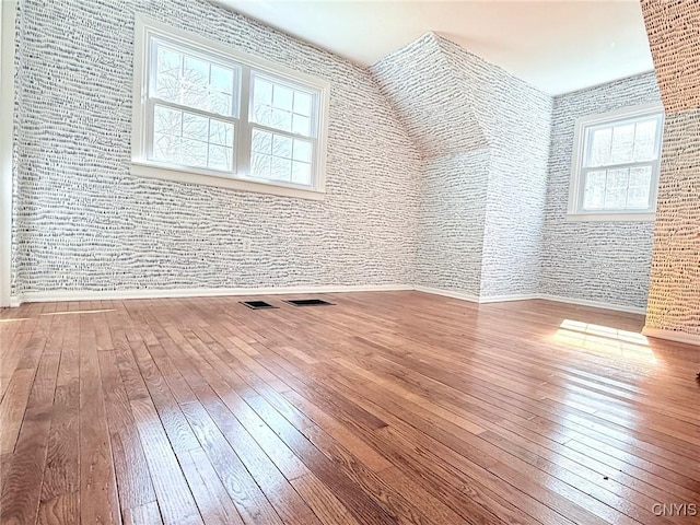 additional living space featuring baseboards, visible vents, and wood-type flooring