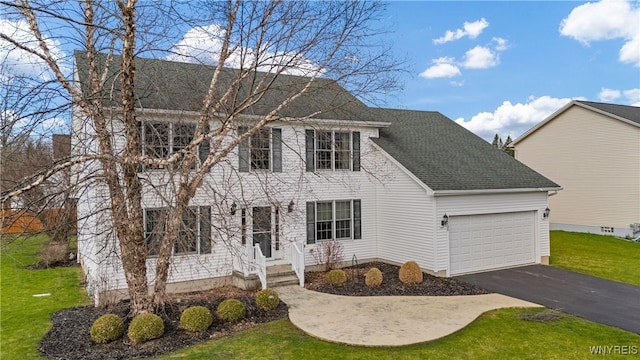 colonial inspired home with a front lawn, driveway, a shingled roof, and a garage