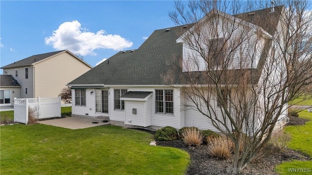 rear view of property with fence, a shingled roof, a yard, and a patio