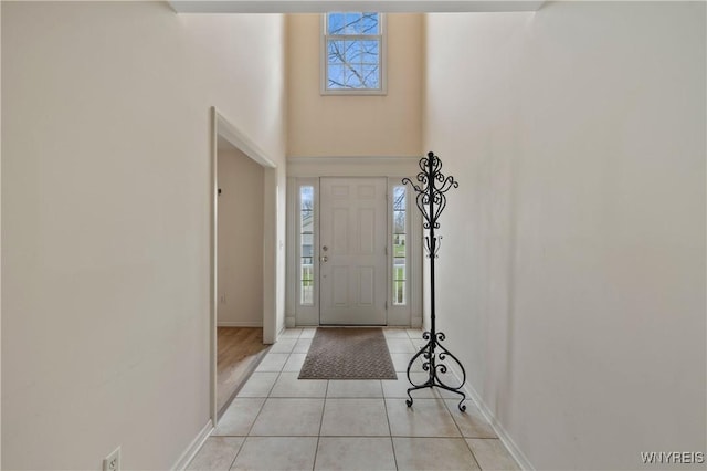 foyer entrance with baseboards, a high ceiling, and light tile patterned floors