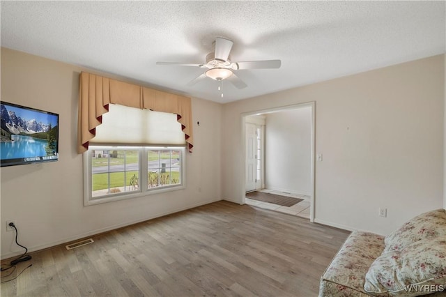 unfurnished living room featuring ceiling fan, baseboards, visible vents, and light wood finished floors