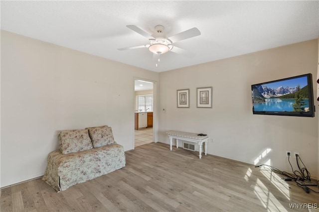living area featuring light wood-type flooring and a ceiling fan