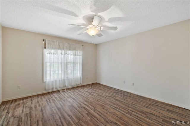 spare room featuring wood finished floors, a textured ceiling, a ceiling fan, and baseboards