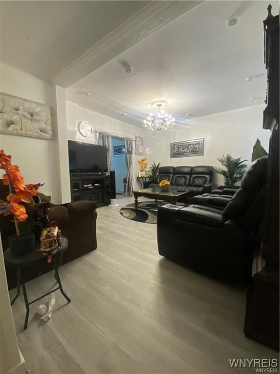 living area with wood finished floors, ornamental molding, and an inviting chandelier
