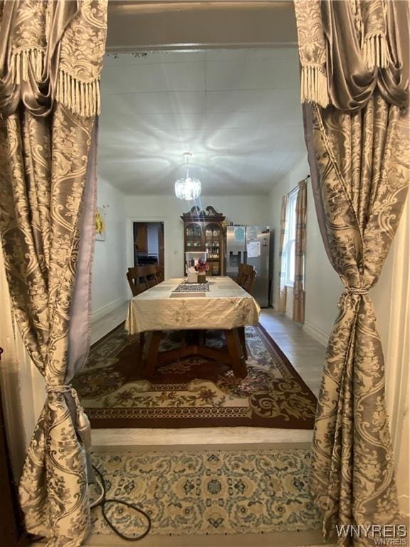 dining room with baseboards, a notable chandelier, and wood finished floors