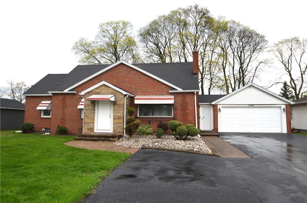 view of front of house with brick siding, an attached garage, driveway, and a front yard