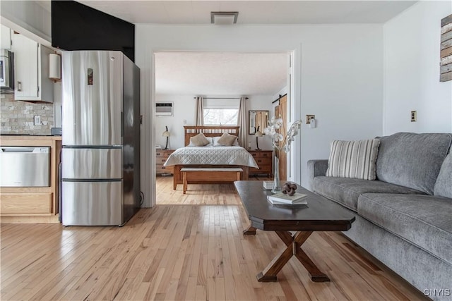 living room featuring a wall mounted AC and light wood-type flooring