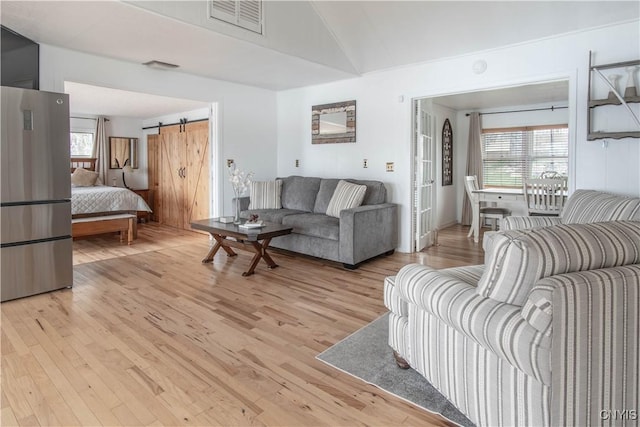 living area featuring visible vents, a barn door, and light wood-style flooring