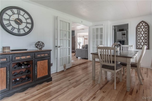 dining room featuring crown molding, french doors, and light wood-type flooring
