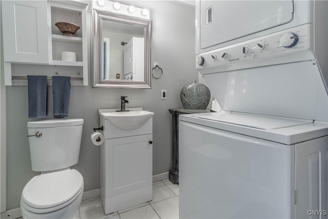 bathroom featuring stacked washing maching and dryer, vanity, baseboards, toilet, and marble finish floor