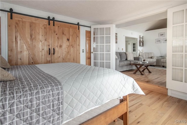 bedroom featuring a barn door and wood finished floors