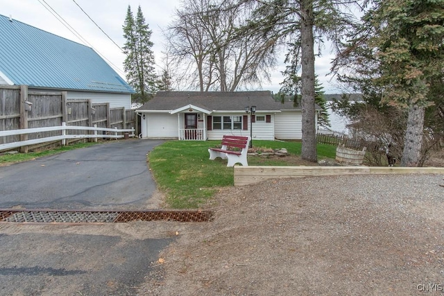 view of front of property featuring a garage, fence, a front yard, and aphalt driveway