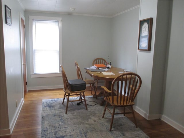 dining room with baseboards, wood finished floors, and crown molding