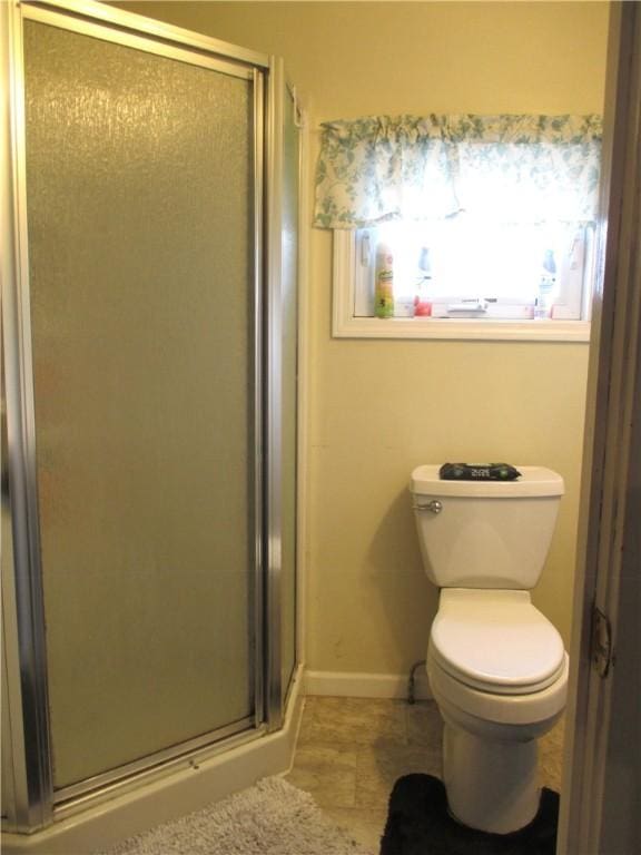 bathroom featuring toilet, baseboards, tile patterned floors, and a stall shower