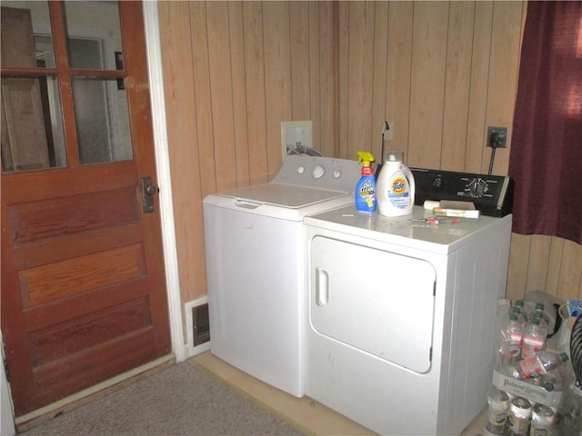 laundry area featuring washing machine and dryer, wood walls, and laundry area