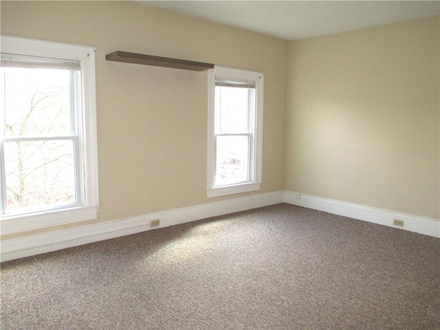 carpeted empty room featuring baseboards