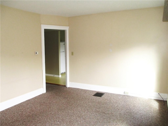 empty room featuring baseboards, visible vents, and carpet