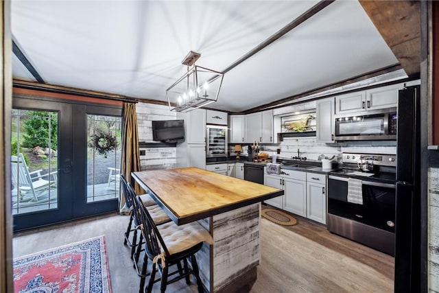kitchen with wood counters, appliances with stainless steel finishes, beverage cooler, and wood finished floors