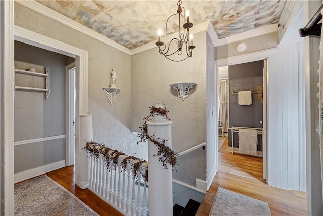 hall with baseboards, wood finished floors, a notable chandelier, and crown molding