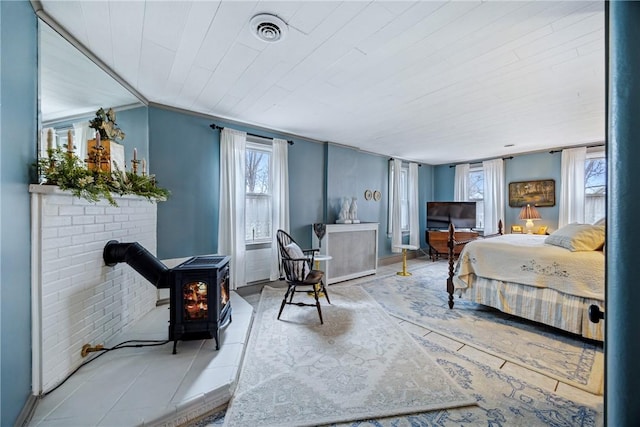 tiled bedroom featuring visible vents and a wood stove
