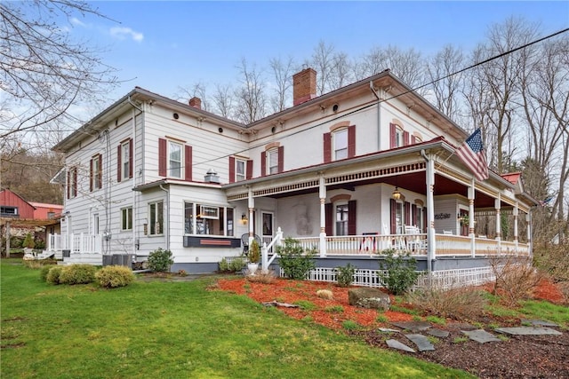 back of property with a yard, a chimney, and covered porch