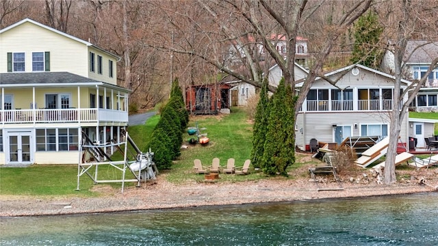 rear view of house featuring a sunroom, a yard, and a water view