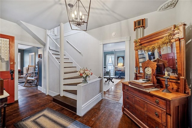 foyer entrance featuring stairs, baseboards, a chandelier, and dark wood-type flooring