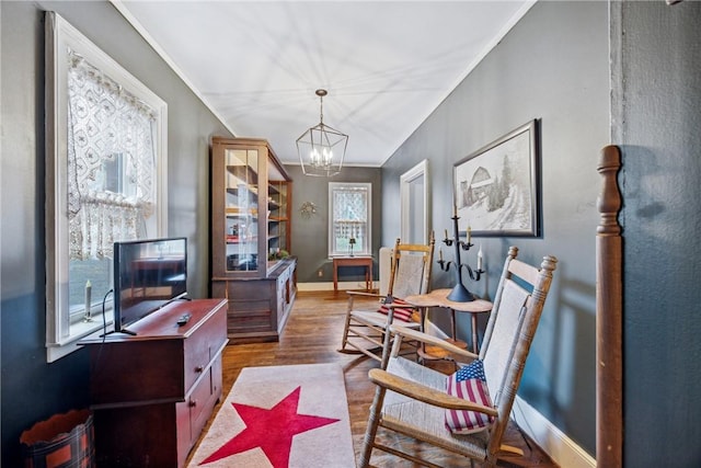 sitting room with wood finished floors, crown molding, baseboards, and an inviting chandelier