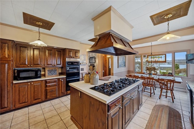 kitchen featuring island exhaust hood, light tile patterned flooring, light countertops, decorative light fixtures, and black appliances