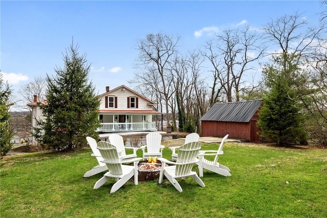 view of yard featuring a fire pit, a storage unit, and an outbuilding