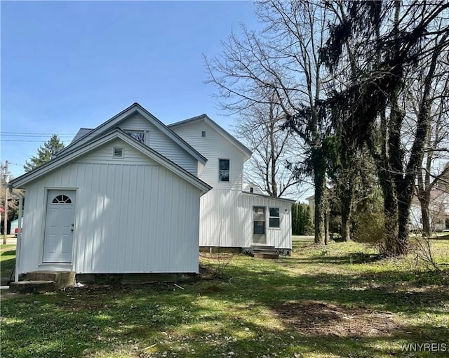 back of house with a lawn and entry steps