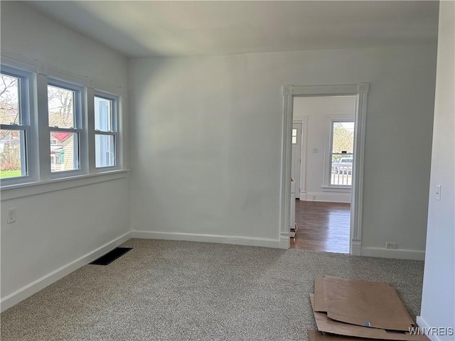 empty room with baseboards, visible vents, and carpet floors