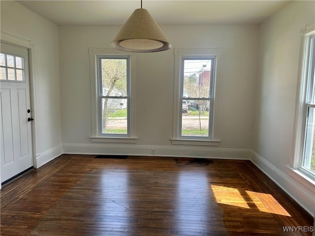 unfurnished dining area featuring baseboards and wood-type flooring