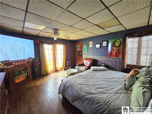 bedroom with wood-type flooring, a paneled ceiling, and ceiling fan
