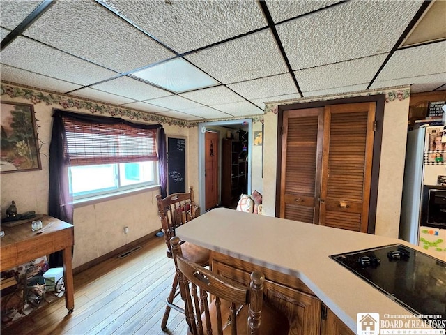kitchen featuring light countertops, visible vents, black electric stovetop, a paneled ceiling, and light wood-style flooring