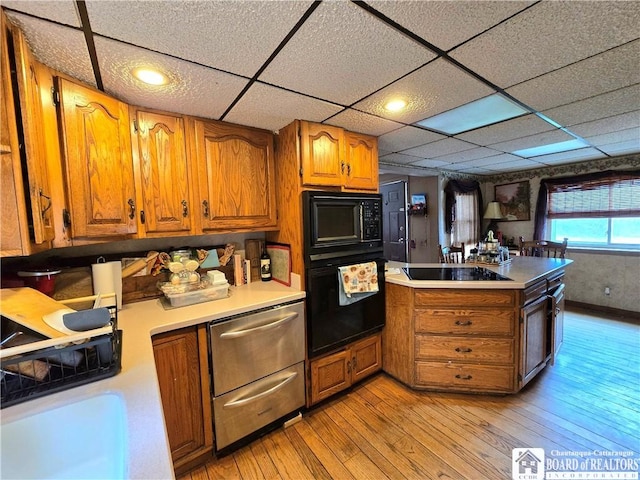 kitchen with black appliances, brown cabinets, and light wood-style flooring