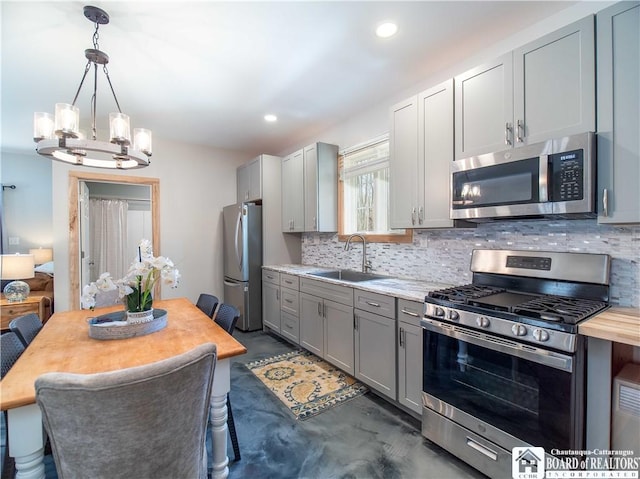kitchen with gray cabinets, appliances with stainless steel finishes, tasteful backsplash, and a sink