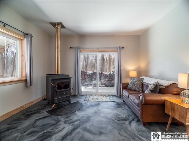 living room with a wood stove, a healthy amount of sunlight, and baseboards