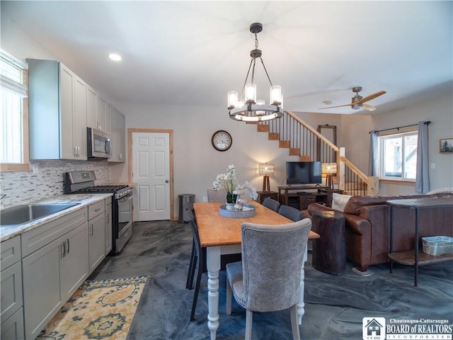 dining space with stairs and ceiling fan with notable chandelier