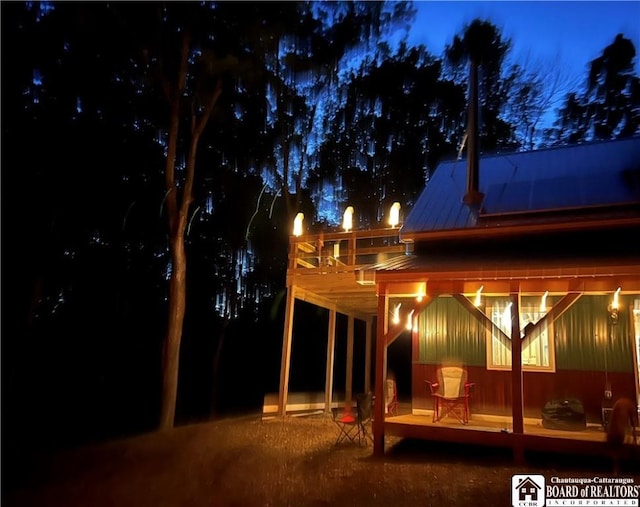 back of house at twilight featuring metal roof