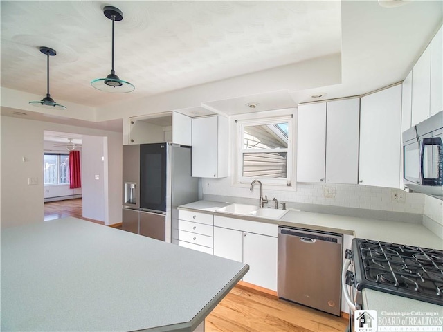 kitchen featuring appliances with stainless steel finishes, a sink, white cabinetry, and light countertops