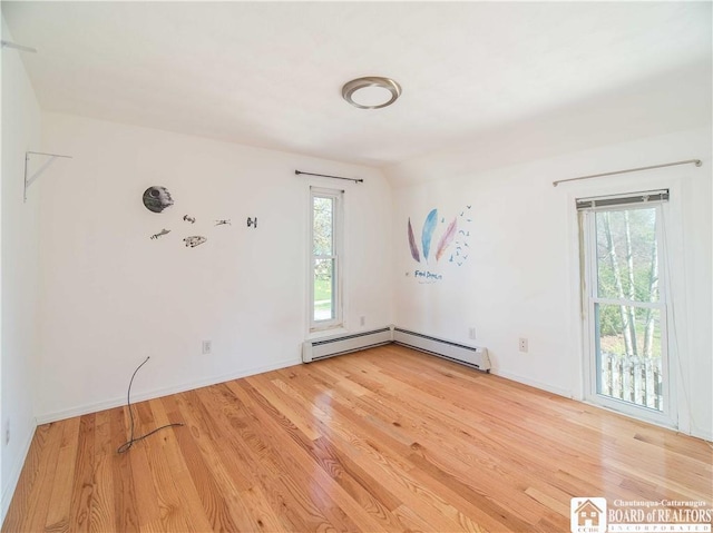 empty room with light wood finished floors, baseboards, and a baseboard heating unit