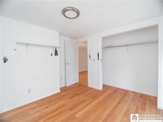 unfurnished bedroom featuring wood finished floors, a closet, and baseboards