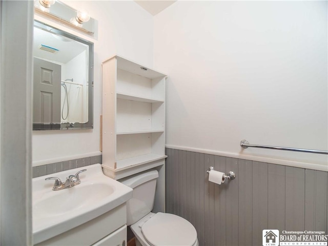 bathroom featuring wainscoting, toilet, vanity, and visible vents