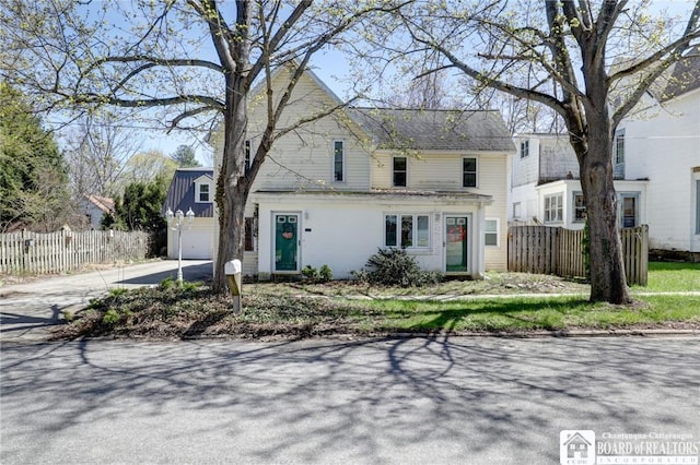 traditional-style home featuring a garage, concrete driveway, and fence