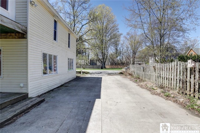 view of side of property with driveway and fence