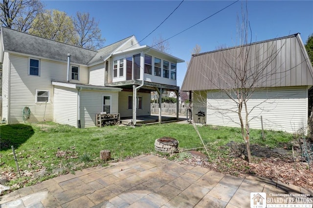 back of property featuring a patio area, an outdoor fire pit, and a yard
